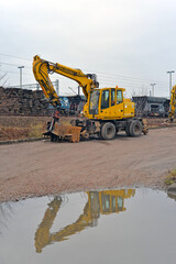 Yellow excavator and reflection in a puddle