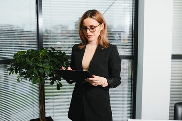Fototapeta premium Portrait of middle age businesswoman standing with digital tablet at office. Business people.