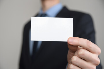 Businessman ,Business Man's hand hold showing business card - close up shot on grey background. Show a blank piece of paper. Paper visit card