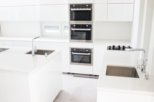 White organised kitchen with modern elements in an apartment . High quality photo