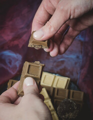 Fototapeta premium The female hands holding a handmade chocolate.Confectionery on a dark background.