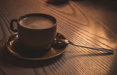 A cup of cappuccino on a wooden table.Evening at the cafe.