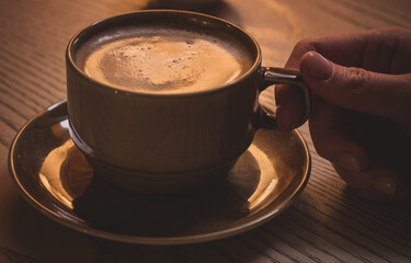 A cup of cappuccino on a wooden table.Evening at the cafe.