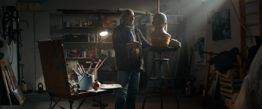 WIDE Portrait of senior adult middle eastern male sculptor working on a bust project in his home garage workshop. Retirement hobby concept. Shot with 2x anamorphic lens