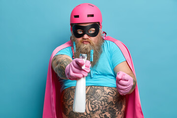 Strict serious bearded man clenches fist from ager sprays detergent at you wears pink helmet eye...