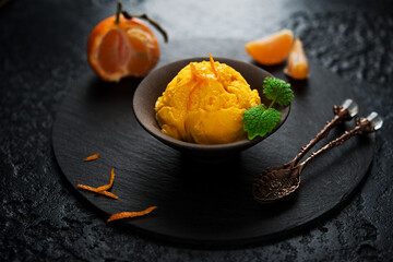 Tangerine ice cream in a cup, sorbet on a black background - obrazy, fototapety, plakaty
