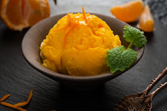 Tangerine ice cream in a cup, sorbet on a black background