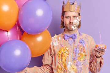 Celebration and party concept. Displeased man feels unhappy after being smeared with cake sad to...