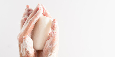 Fototapeta premium Washing of hands with soap. Cleaning hands. Closeup on young woman hands with soap bar on white background.