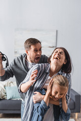  man holding waist belt near crying wife and child at home