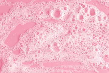 White soap foam on pastel pink background. Flat lay, top view, copy space