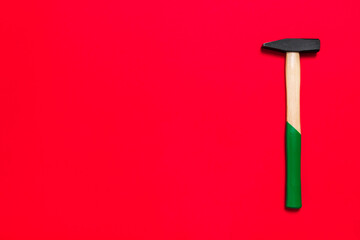 Hammer is isolated on a red background with place for text. Shop banner with construction tools. New Year or Christmas festive backdrop. One of the basic home use instrument for hammering nails