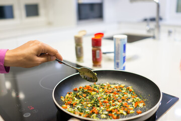 Frying pan on stove with pepper and mushrooms, closeup