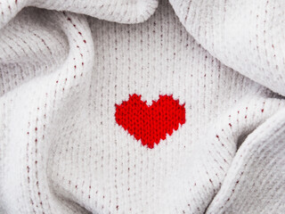 Red heart shape on white fabric texture.