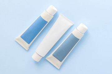 three tubes with cosmetic creams on a blue background, beauty concept 