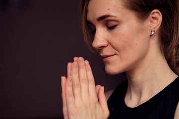 middle aged woman meditating with her eyes closed, practicing Yoga with hands in prayer position.