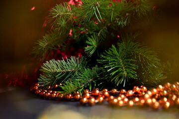 Winter background for New Year and Christmas, fir branches, tinsel, Christmas tree decoration, orange beads, blurry lights.