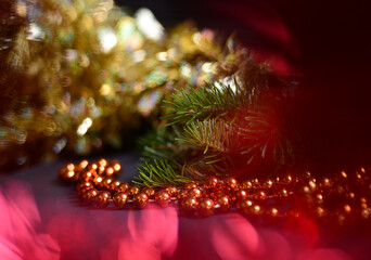 Orange beads with round beads to decorate the Christmas tree, close-up against a background of blurred red light from the lamps. 