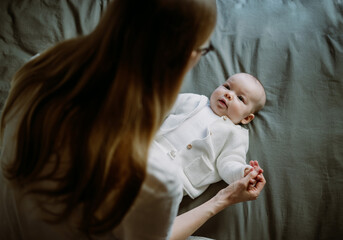 Beautiful mother with her baby. Young beautiful woman looks at her little daughter. Baby girl laughing in her mother's arms.