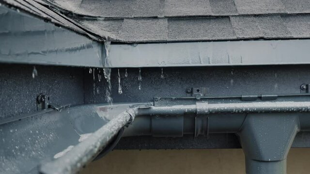 Jets of rain drain into the drainage system on the roof of the house