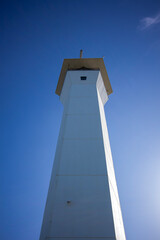 Tall white lighthouse against the blue sky 