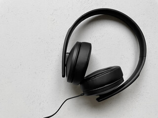 pair of black over-ear headphones on off-white background with copy space