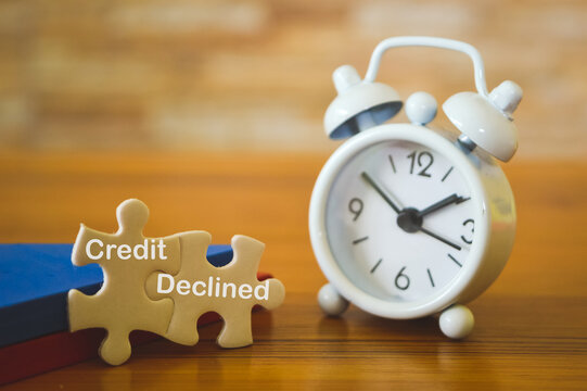 Selective focus of clock, wooden blocks and white puzzles written with text CREDIT DECLINED. Business concept.