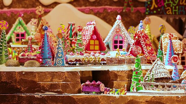 A toy city of gingerbread houses and a railway. The train drivers travel through the fabulous children's city. Edible gingerbread maker with icing. Christmas decoration in the panorama.