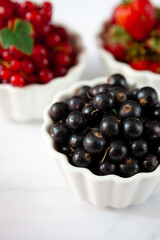 Berry in a plate on a white background. Black currant. Summer berries on the table. Vitamin healthy food. Currant.