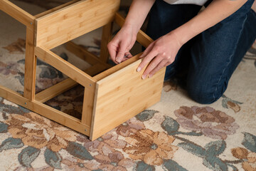 Teen boy assembles furniture according to the instructions - a wooden chair. Housework and order in...