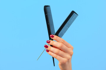 Female hand holding hair comb against blue background