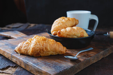 Breakfast bread, croissants and fresh milk on the wooden table.