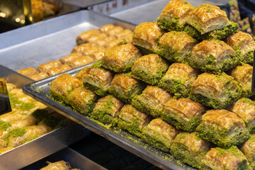 Traditional Turkish baklava with pistachios on the big trays in kitchen.