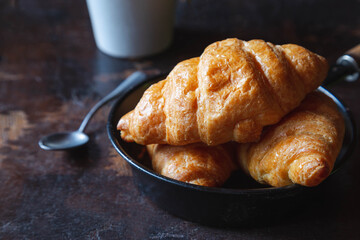 Breakfast bread, croissants and fresh milk on the wooden table.