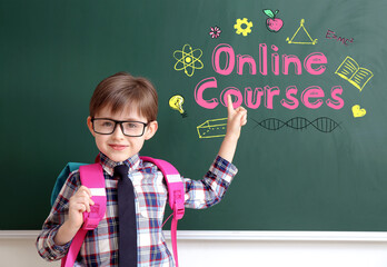 Cute little schoolboy pointing at blackboard with written text 