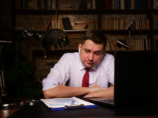 Overworking. Tired pensive worker late at the workplace in the office.