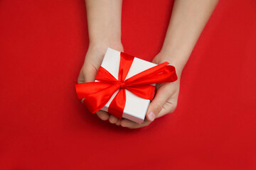 Children's hands hold gift box on a red background. A concept by the Mother's Day.  Father's day....