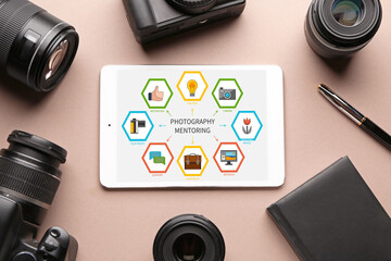 Tablet computer with interface of mentoring program on screen and set of photographer's equipment on color background