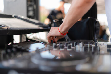 DJ playing music at outdoor event. Person operating mixer at music festival. Close up shot of...