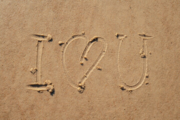 I love you sign whiten on the sand at the beach. Romantic love symbol at tropical seashore at sunset.