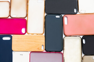 Pile of multicolored plastic back covers for mobile phone. Choice of smart phone protector accessories on white background. A lot of silicone phone backs or skins next to each other