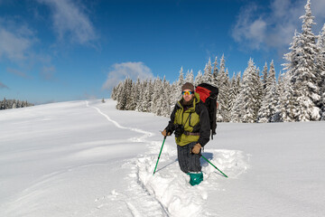 Fototapeta na wymiar A photographer hiking in the winter mountains