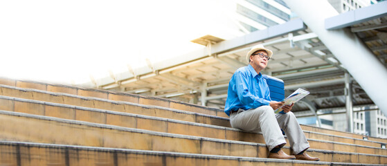 Senior man traveling with luggage sitting on staircase checking city map and sightseeing Travel and tourism concept.Elderly Travel and tourism concept.