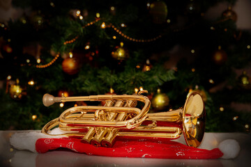 Cornet – brass musical instrument – placed on Santa’s hat with a Christmas tree in the background. Festive holiday atmosphere with warm lights and musical charm.