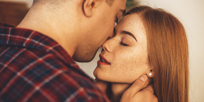 Close up photo of a caucasian ginger lady with freckles embracing with her lover having a intimate moment together