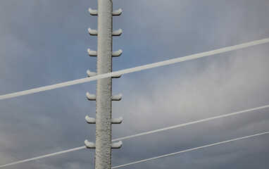 power lines frozen by a large layer of ice in the shape of a cylinder with icicles. icing loads the...