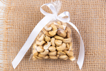 cashew nuts in a gift transparent package on sacking on a white background