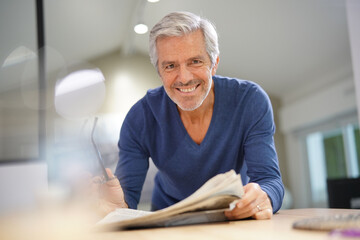 Senior man at home relaxing and reading newspaper
