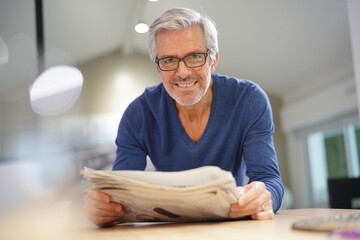 Senior man at home relaxing and reading newspaper