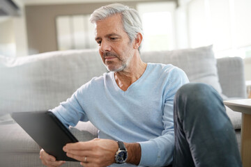 60-year-old man at home connected with digital tablet